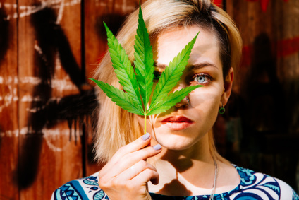 Beautiful girl with a cannabis leaf near the face
